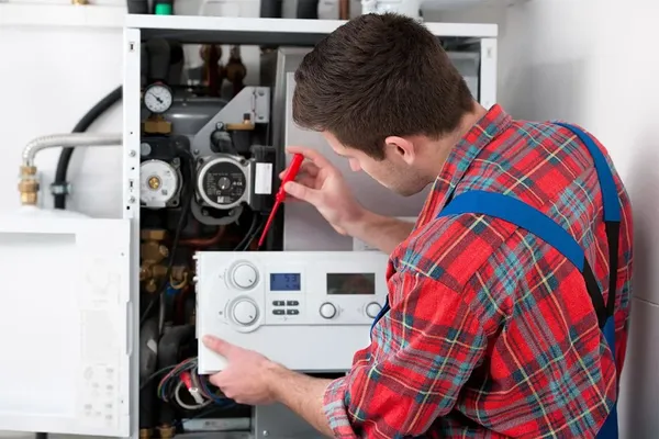 Plumber repairing a water heater, checking components and settings, emphasizing emergency plumbing services in Butler County